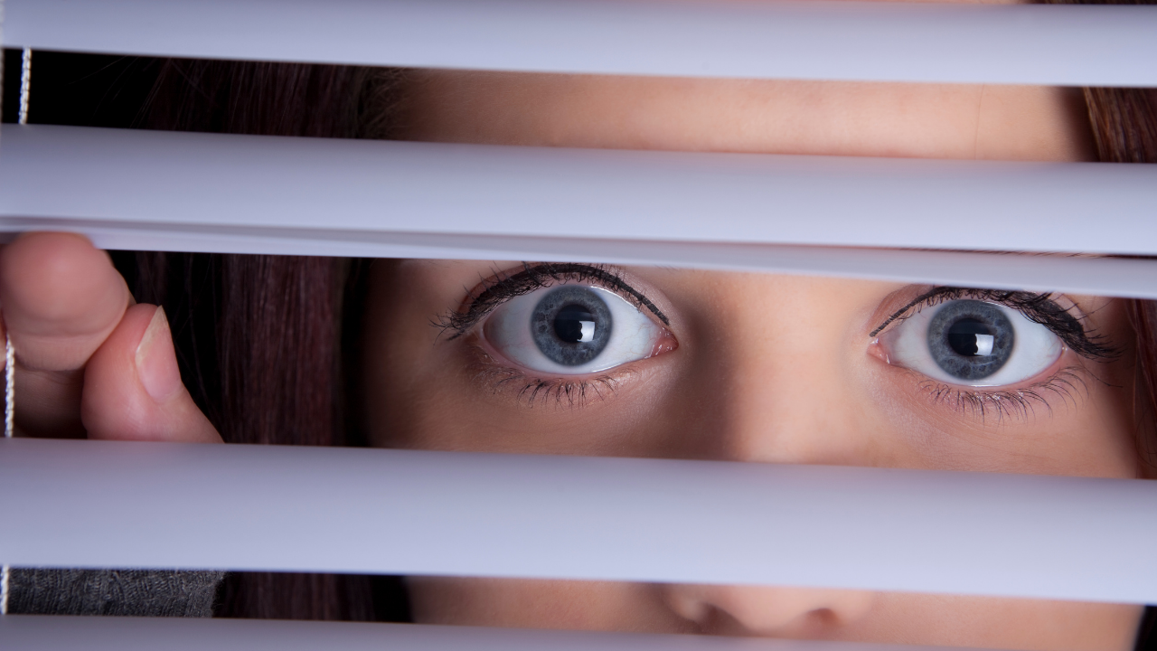 Woman peering through blinds